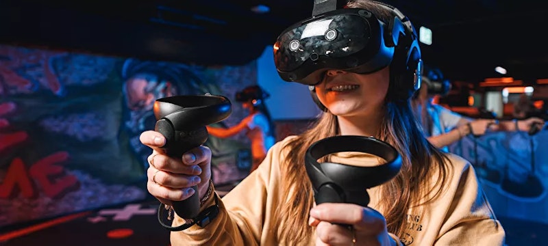 A girl fully immersed in the Ghost Patrol VR game at Playrena Roosendaal, battling ghosts in an action-packed, thrilling virtual reality adventure.